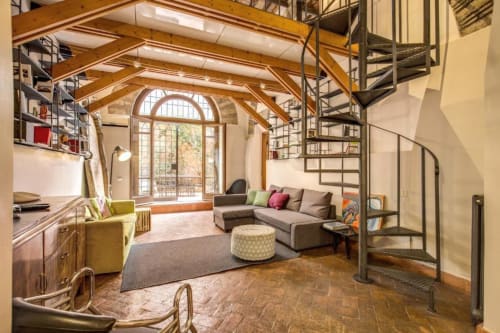 Appartamento Smart Loft a Roma con camera in loft, travi a vista, divano, angolo cottura e finestre ad arco