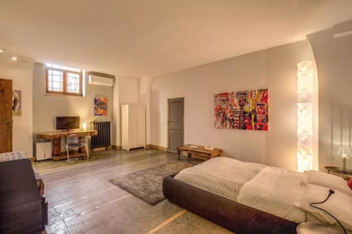 Smart Loft moderno a Roma con camera da letto, scrivania, zona living e angolo cottura con arredamenti contemporanei e opere d'arte
