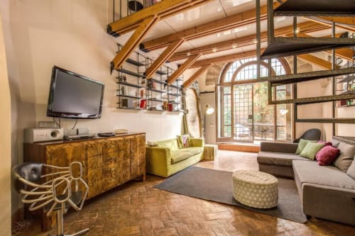 Appartamento Smart Loft a Roma con soffitti a travi a vista, mobili in legno, divano verde e comfort moderni