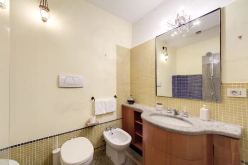 Bagno moderno in Smart Loft a Downtown Srl Roma con piastrelle gialle, lavabo curvo, specchio e bidet