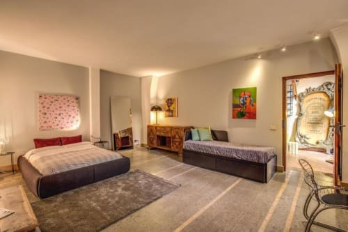 Ampia camera da letto Smart Loft a Roma con due letti, mobili in legno, opere d'arte colorate e dotazioni moderne in ambiente luminoso