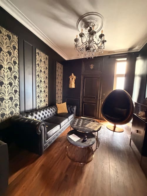 Élégant salon noir et or à La Maison Defendue avec lustre, canapé Chesterfield et mobilier contemporain