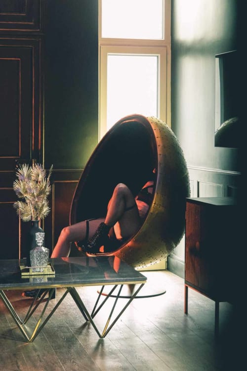 Intérieur moderne de La Maison Defendue avec fauteuil pod rouge, table en verre, fleurs séchées et lumière naturelle