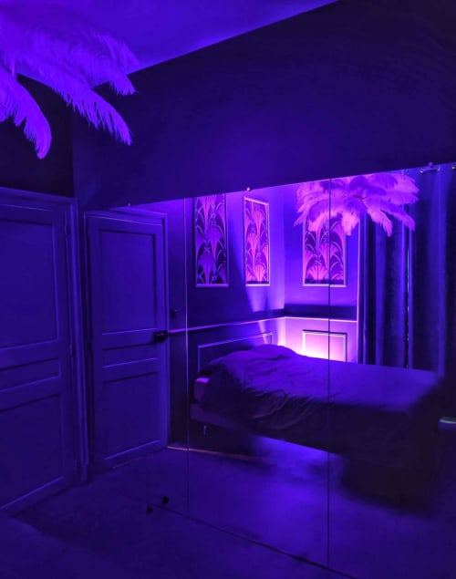 Chambre moderne avec éclairage néon violet, paroi vitrée, lit et œuvre d'art palmier tropical à l'hôtel La Maison Defendue