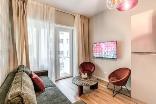 Soggiorno moderno dell'appartamento The Cloud a Roma, con sedie bordeaux, divano, pavimenti in legno e accesso al balcone