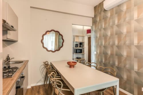 Cucina e zona pranzo moderna nell'appartamento The Cloud presso Downtown Srl Roma con tavolo bianco, sedie in legno e geometrico