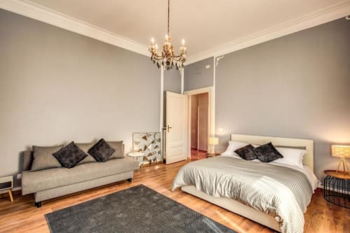 La Grande Camera da Letto Retrò a Roma con letto, divano, lampadario, parquet e arredi moderni