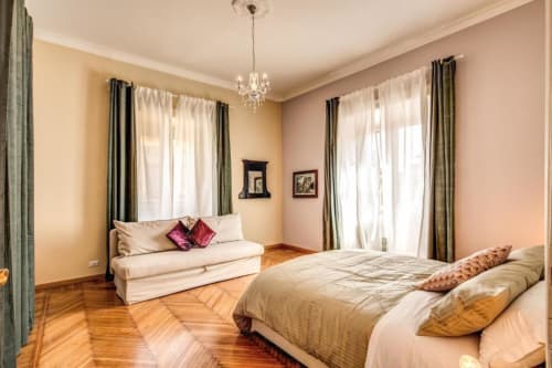 Ampia camera da letto nell'appartamento The Great Retro a Roma, con parquet, letto matrimoniale, divano, lampadario di cristallo e doppio