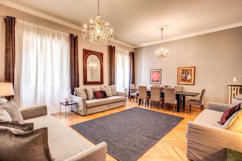 Elegante soggiorno retrò a Roma con lampadari, arredi neutrali, pavimenti in legno e arredamento contemporaneo