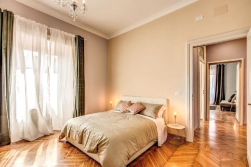 Camera da letto elegante nel Great Retro apartment a Roma con pavimenti in legno, letto matrimoniale e ampie finestre con tende in tulle