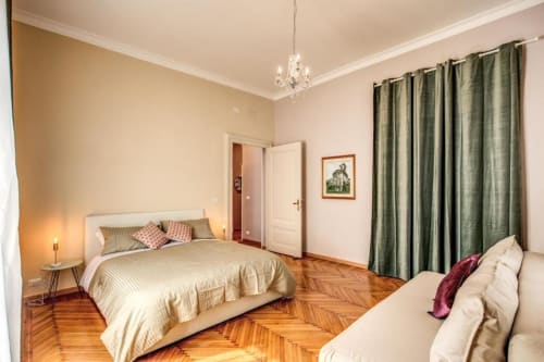 Elegante camera da letto retrò a Roma con parquet in legno, letto, divano, tende verdi e lussuoso lampadario