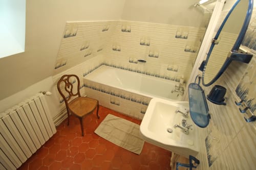 Bathroom at La Suite de la Tour with bathtub, sink, bidet, red tile floor, and decorative wallpaper at Domaine de Bort near
