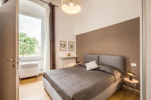 Camera da letto moderna con letto grigio, parete accent tortora, lampada a sospensione e vista mare nell'appartamento di Cinque Terre
