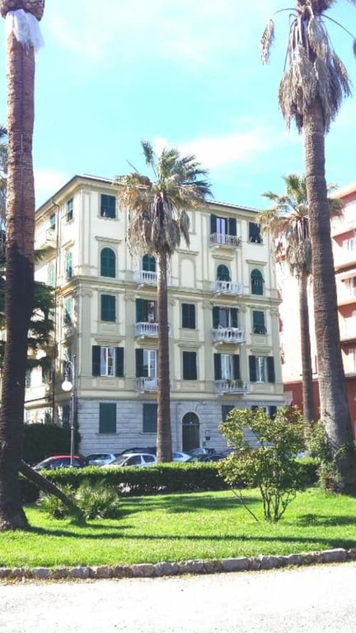 Elegante edificio color crema a Cinque Terre con palme e giardino curato, affacciato sul mare in Italia