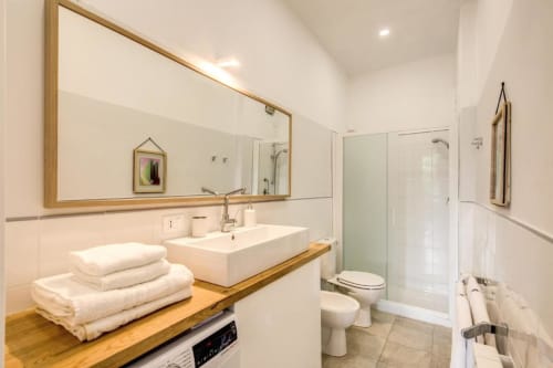 Bagno moderno con doppio lavabo, mobile in legno, grande specchio e doccia in vetro nell'appartamento a Cinque Terre