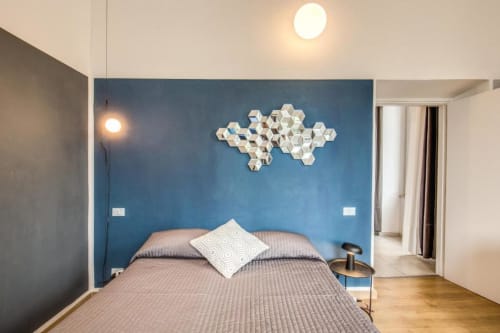 Camera da letto moderna con parete accent blu, arte murale esagonale bianca e pavimento in legno nell'appartamento a Cinque Terre