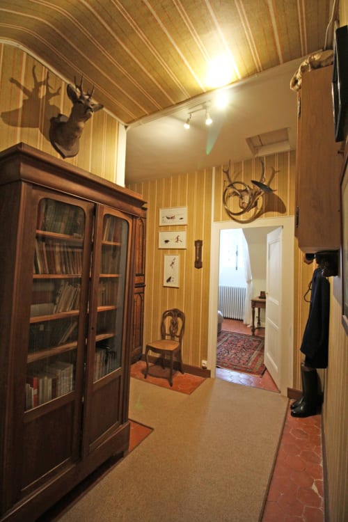 Historic room corridor at Domaine de Bort, decorated with taxidermied deer head, wooden furniture, and vintage furnishings