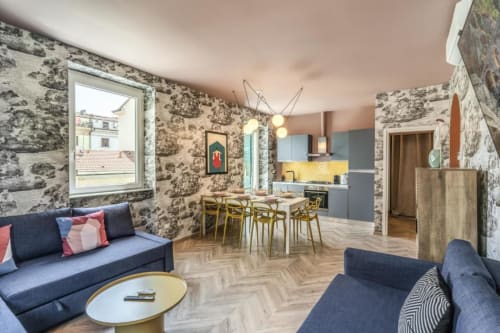 Moderno appartamento delle Cinque Terre con pareti decorate, divano blu, zona pranzo, cucina attrezzata e pavimenti in legno.