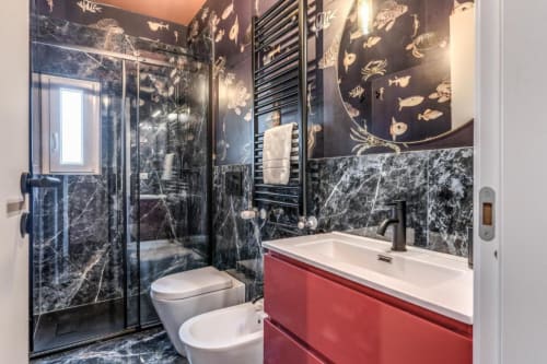 Bagno di lusso nell'appartamento Cinque Terre Swing con pareti in marmo scuro, vanità rossa, doccia a cascata e opera d'arte con pesci dorati