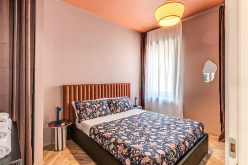 Camera da letto moderna nell'appartamento Cinque Terre Swing con testata arancione, biancheria floreale e illuminazione calda, Roma