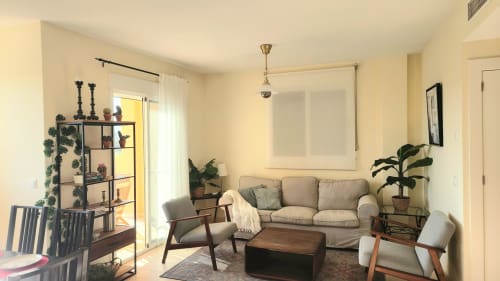 Luminosa sala de estar en BAKIT HOUSE en Águilas con sofá beige, muebles de madera, plantas en maceta y vistas al mar desde el balcón