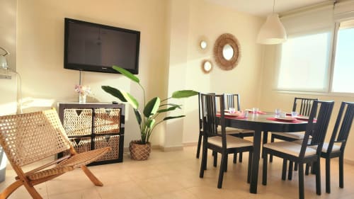 Comedor moderno con vistas al mar en BAKIT HOUSE, Águilas, con mesa negra, almacenamiento de ratán y ambiente tropical