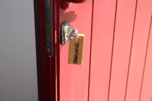 Red door with chrome lever handle and wooden key tag at Monte da Morena rural guesthouse in Serpa, Portugal