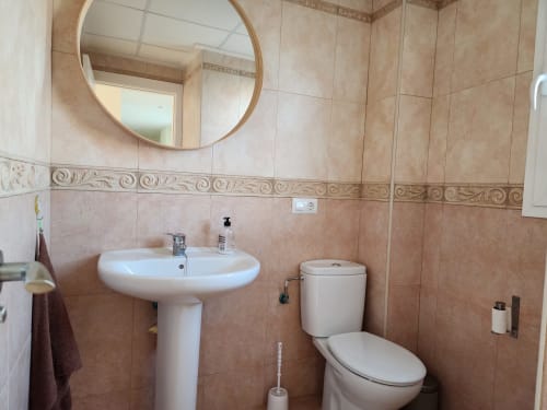 Baño moderno en BAKIT HOUSE en Águilas con lavamanos pedestal, espejo redondo y inodoro