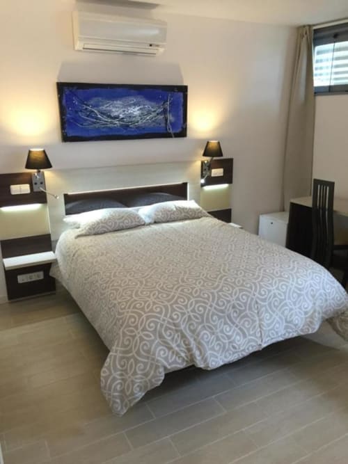 Modern family room at Hotel Skyline Alcorcón with queen bed, dark wood furniture, wall-mounted TV, and air conditioning