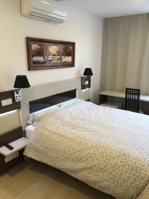 Modern hotel room at Hotel Skyline Alcorcón with queen bed, black nightstands, landscape artwork, and air conditioning unit