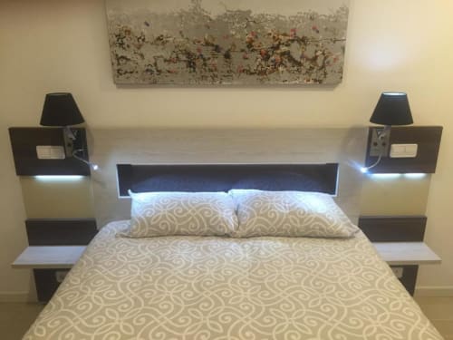 Modern hotel bedroom at Hotel Skyline with queen bed, black headboard, bedside lamps, patterned bedding, and abstract