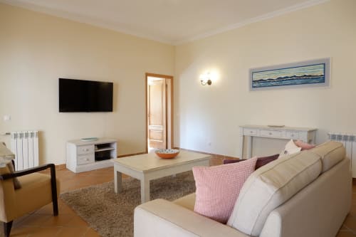 Spacious living room at Be SilverCoast with beige sofa, wall-mounted TV, coffee table, and ocean-view artwork in Serra D'El