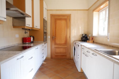 Modern kitchen in A Casa dos Príncipes apartment at Be SilverCoast, Serra D'El Rei with white cabinetry and terracotta tile