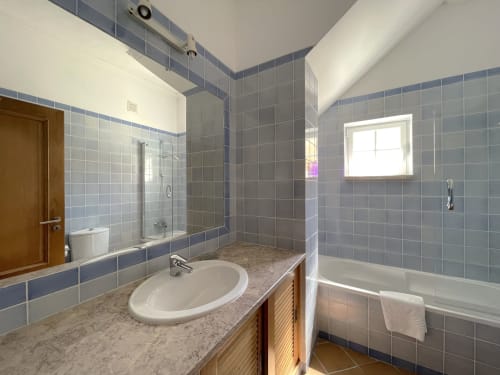 Modern bathroom at Be SilverCoast hotel in Serra D'El Rei with blue tile walls, granite countertop, round sink, and shower