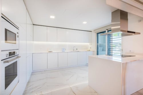 Cozinha moderna branca com piso em mármore, bancada em ilha e eletrodomésticos em aço inoxidável no luxo Atlantic Places