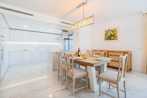 Cozinha e sala de jantar em moderno apartamento de luxo em Albufeira, com armários brancos, mesa de madeira e vista para a cidade no Atlantic