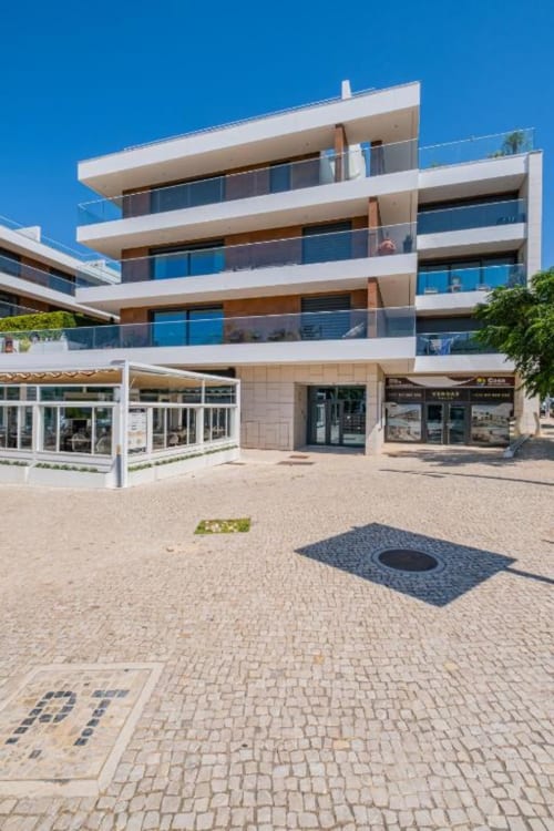Edifício de luxo Atlantic Places com múltiplos andares em Albufeira, com varandas em vidro e lojas no piso térreo