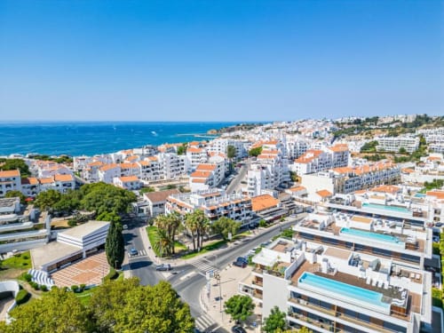Vista aérea de Albufeira com apartamentos Atlantic Places, edifícios de telhados laranja, piscinas e litoral Mediterrâneo