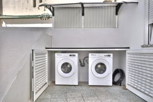 Lavandaria do apartamento Atlantic Places Albufeira com duas máquinas de lavar brancas e armários de armazenamento