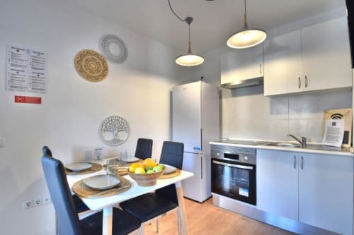 Cozinha e sala de jantar modernas no apartamento Atlantic Places no centro histórico de Albufeira com móveis brancos e vista para a cidade
