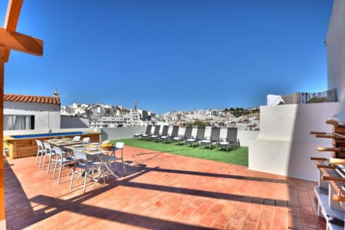 Terraço do apartamento Atlantic Places em Albufeira com vista da cidade, zona de refeições, espreguiçadeiras e paisagem de casarões na encosta