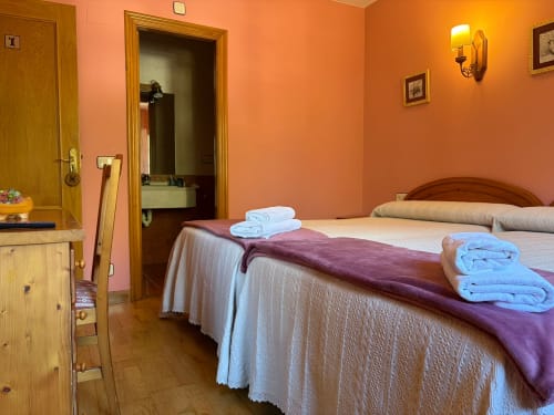 Habitación doble en Hotel Restaurante Casa Manolo, Adra con camas gemelas, paredes naranjas, muebles de madera y baño privado