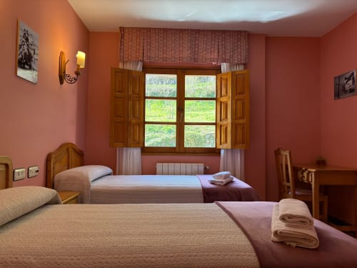 Acogedora habitación doble en Hotel Restaurante Casa Manolo en Adra con dos camas, muebles de madera y vistas al campo