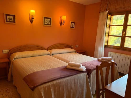 Luminosa habitación naranja con dos camas en Casa Manolo hotel en Adra, con muebles de madera y vistas al jardín