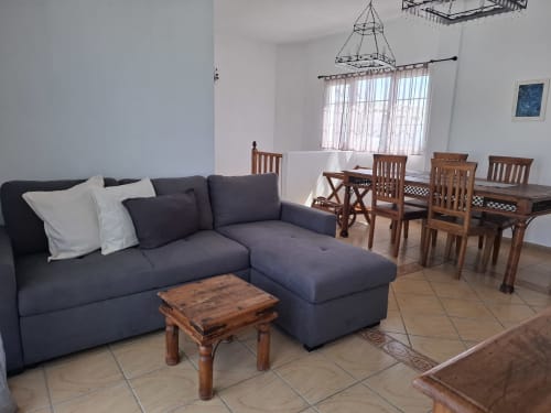 Modern living room with dark blue sectional sofa and wooden dining table in Villa 9 at Villas del Mar, Puerto Calero