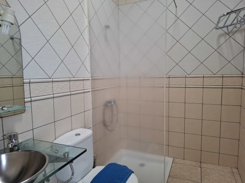 Modern bathroom at Villas del Mar with glass shower enclosure, tiled walls, sink, and toilet in Puerto Calero