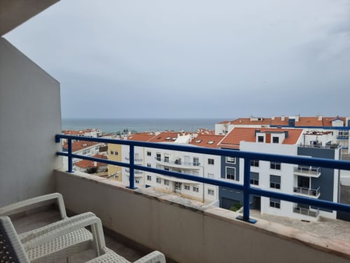 Balcony view of Ericeira coastal town with white and terracotta-roofed buildings overlooking the ocean