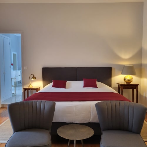 Chambre élégante au Logis des Tourelles à Cognac avec tête de lit sombre, touches bourgognes et éclairage chaleureux