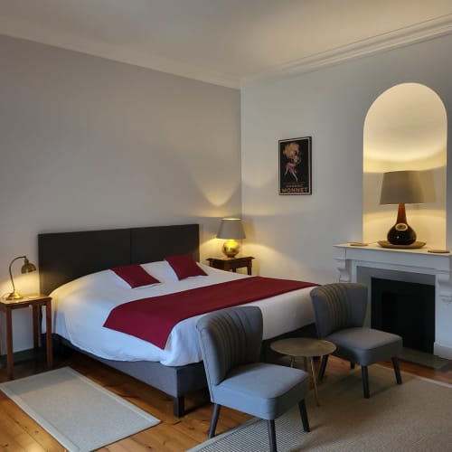 Chambre élégante du Logis des Tourelles avec lit queen-size, parure bordeaux et mobilier moderne