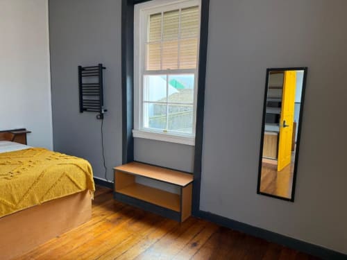 Quarto luminoso na Golden Mermaid Villa com cama em amarelo, pisos de madeira, espelho com moldura preta e vista pela janela